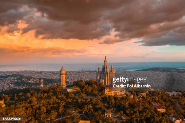 aerial view of sacred heart basilica on top of tibidabo near barcelona during sunset. - barcelona aerial stock pictures, royalty-free photos & images