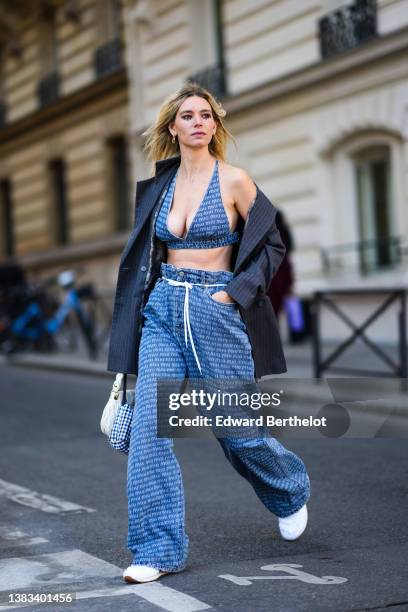 Natalia Verza wears a gold earring from Fendi, a blue with white Miu Miu inscriptions print pattern denim V-neck / cropped bra underwear, matching...