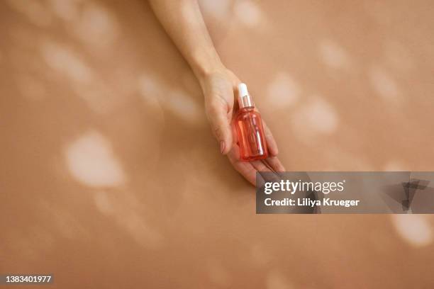 woman’s hand holding glass bottle with cosmetic liquid. - pipette stock-fotos und bilder