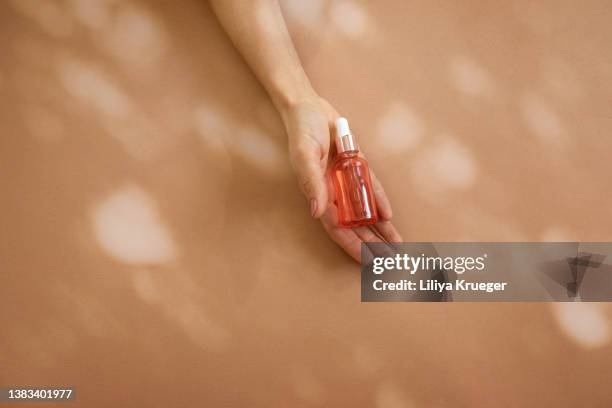 woman’s hand holding glass bottle with cosmetic liquid. - perfume photos et images de collection