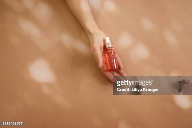 woman’s hand holding glass bottle with cosmetic liquid. - woman cosmetics stock pictures, royalty-free photos & images