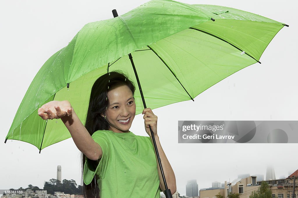 Happy woman holding an umbrella in the rain