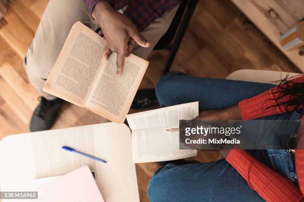 unkenntlicher mann und frau, die den roman analysieren, während sie in der bibliothek lesen - two men studying library stock-fotos und bilder