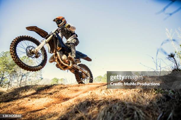 dirtbiker doing a jump in a wooded area - motocross photos et images de collection