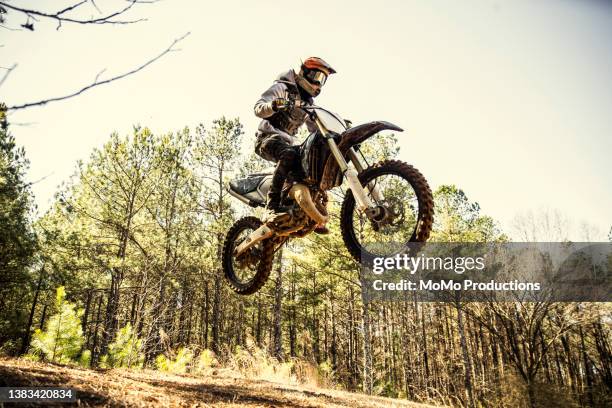 dirtbiker doing a jump in a wooded area - motocross photos et images de collection