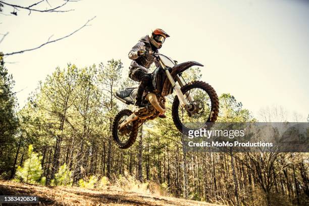 dirtbiker doing a jump in a wooded area - motocross stock pictures, royalty-free photos & images