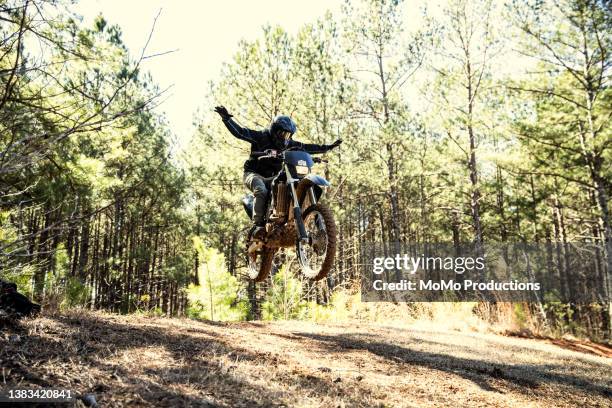 dirtbiker doing a jump with no hands in a wooded area - freihändiges fahrradfahren stock-fotos und bilder