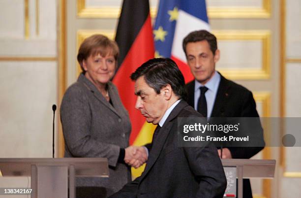 French President Nicolas Sarkozy shakes hands with German chancellor Angela Merkel as French Prime minister François Fillon leaves after a news...