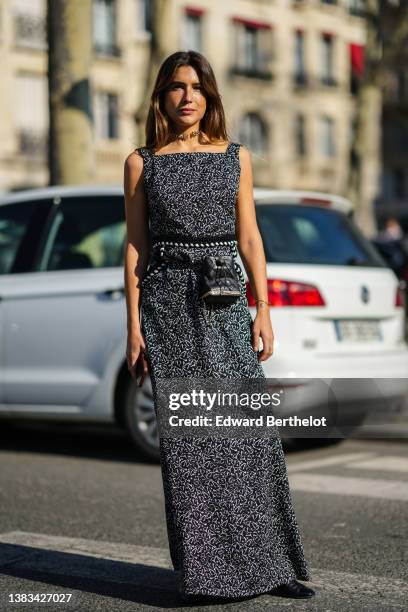 Belen Hostalet wears a silver chain necklace from Chanel, a black with white print pattern tank-top long dress with pompom belt, a black shiny...