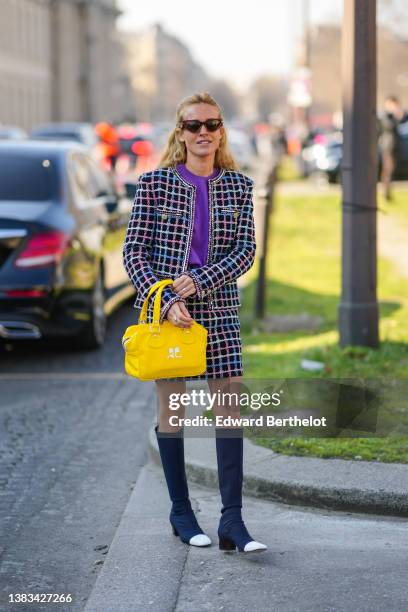 Blanca Miro wears red sunglasses, a purple wool pullover, a gold ring, a black with white / pink / blue checkered print pattern tweed jacket from...