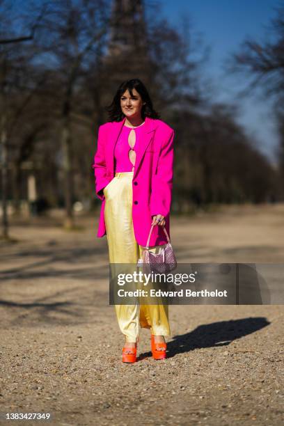 Clervie Rose wears a neon pink oversized blazer jacket, a neon pink cut-out circle t-shirt, high waist gold large pants, a pink rhinestones Reedition...