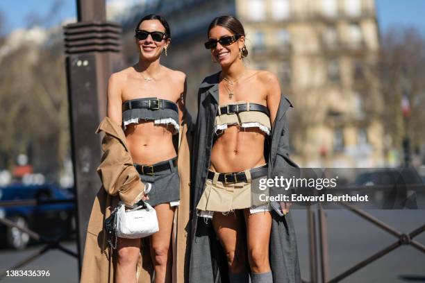 Simona Carlucci wears black sunglasses, a dark gray ripped shoulder-off / cropped top with a large leather belt from Miu Miu, a matching dark gray...