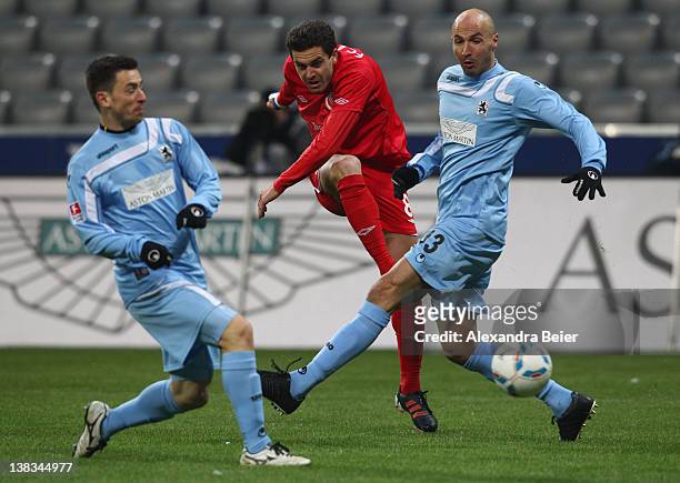 Dimitar Rangelov of Energie Cottbus shoots against Necat Ayguen and Antonio Rukavina during the German second league match between 1860 Muenchen and...