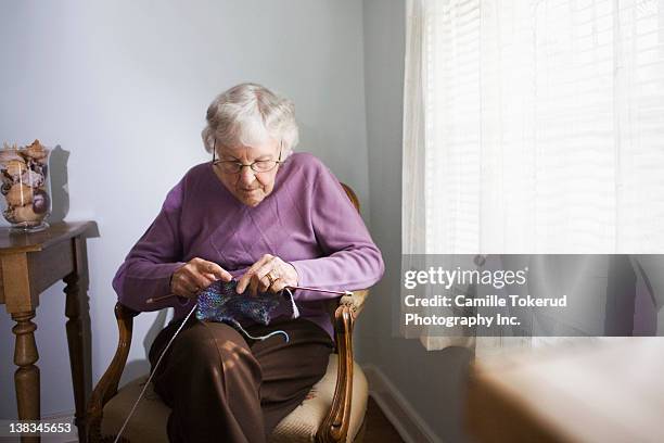 elderly woman knitting at home - knit stockfoto's en -beelden