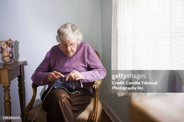 elderly woman knitting at home - knitting stock pictures, royalty-free photos & images