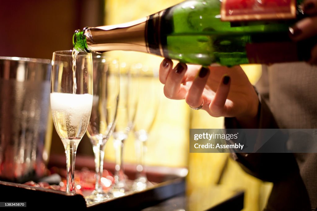 Hotel staff member pours champagne into glasses