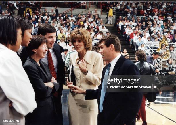 The University of Connecticut women's basketball coaches Geno Auriemma and Chris Dailey talk with Notre Dame coach Muffet McGraw before a game,...