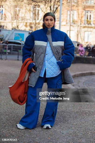 Taqwa Bintali wears a green head scarf, boxy blue and gray Egon Lab down jacket, blue and white striped top, boxy blue cargo pants, and oversized...