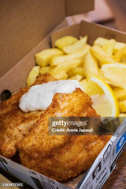 fish and chips take away in box with tartar sauce on top, selective focus, copy space - fish chips stockfoto's en -beelden