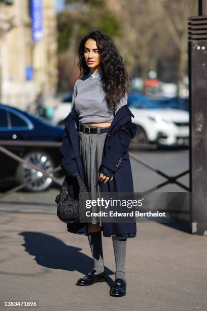 Jessica Kahawaty wears a blue cropped shirt from Miu Miu, a pale gray cropped pullover, a black shiny leather belt from Miu Miu, a gray pleated /...