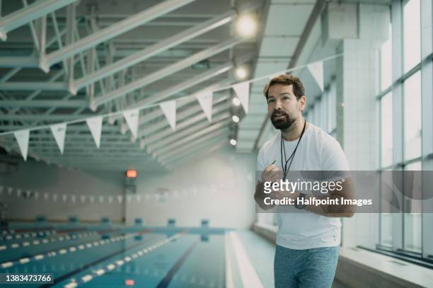 personal coach encouraging swimmer when swimming indoors in swimming pool. - swim coach stock pictures, royalty-free photos & images