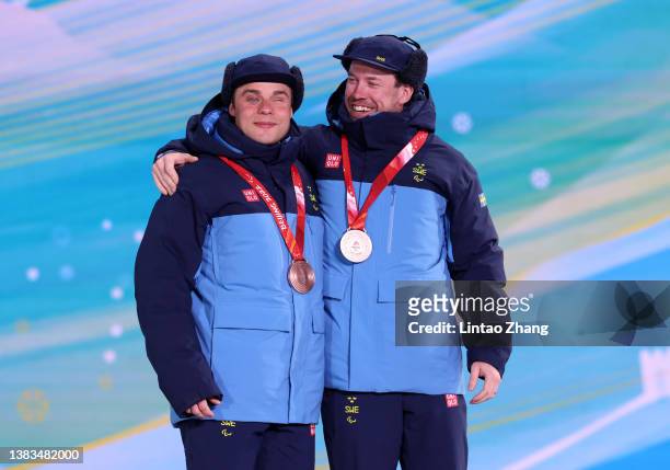 Bronze medalist Zebastian Modin of Team Sweden celebrates on the podium with his guide during the medal ceremony for the Men's Sprint Free Technique...