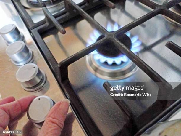 gas cooker top view, hand turning off gas - ガス台 ストックフォトと画像