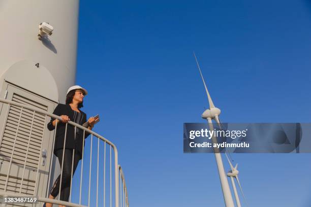 businesswoman is checking wind turbine renewable energy with digital tablet . - airboard stock pictures, royalty-free photos & images