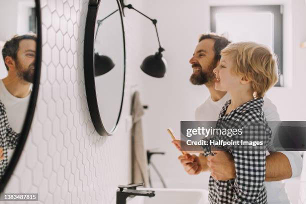 father with small child indoors in bathroom in the morning at home, brushing teeth. - lavarsi i denti foto e immagini stock