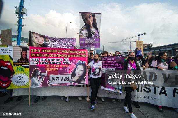 Mothers and relatives of feminicide victims hold signs with pictures and names of their relatives as women participate in the International Womens...