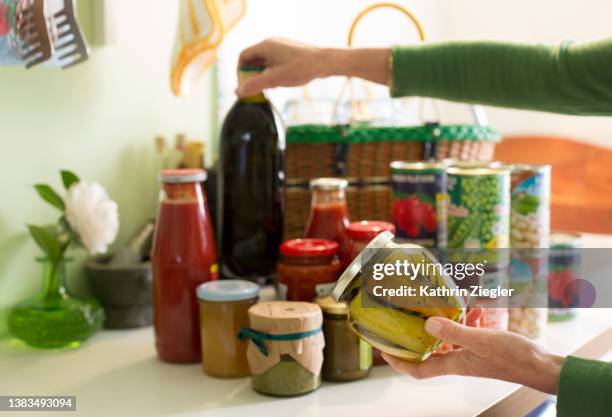 woman unpacking groceries on kitchen counter, canned and preserved foods - durability stock pictures, royalty-free photos & images