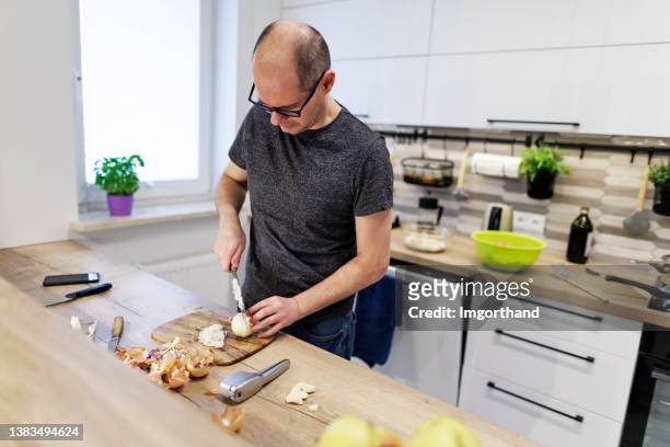 middle age man chopping onion in modern kitchen - chopping stock pictures, royalty-free photos & images