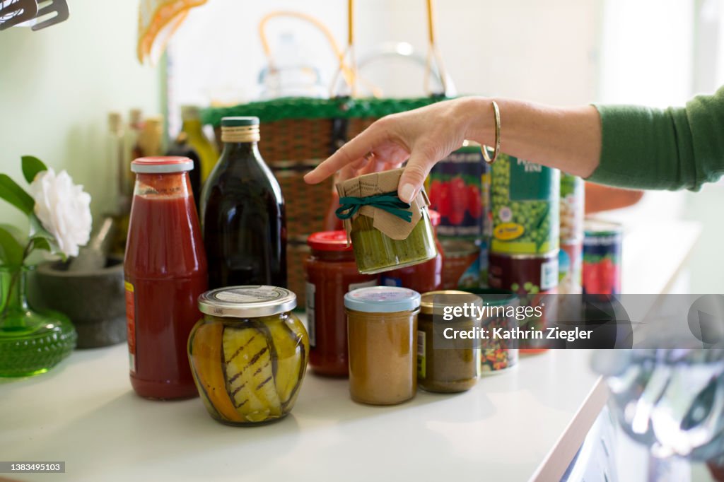 Woman unpacking groceries on kitchen counter, canned and preserved foods