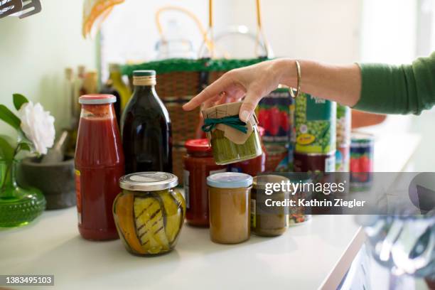 woman unpacking groceries on kitchen counter, canned and preserved foods - acquisti dettati dal panico foto e immagini stock