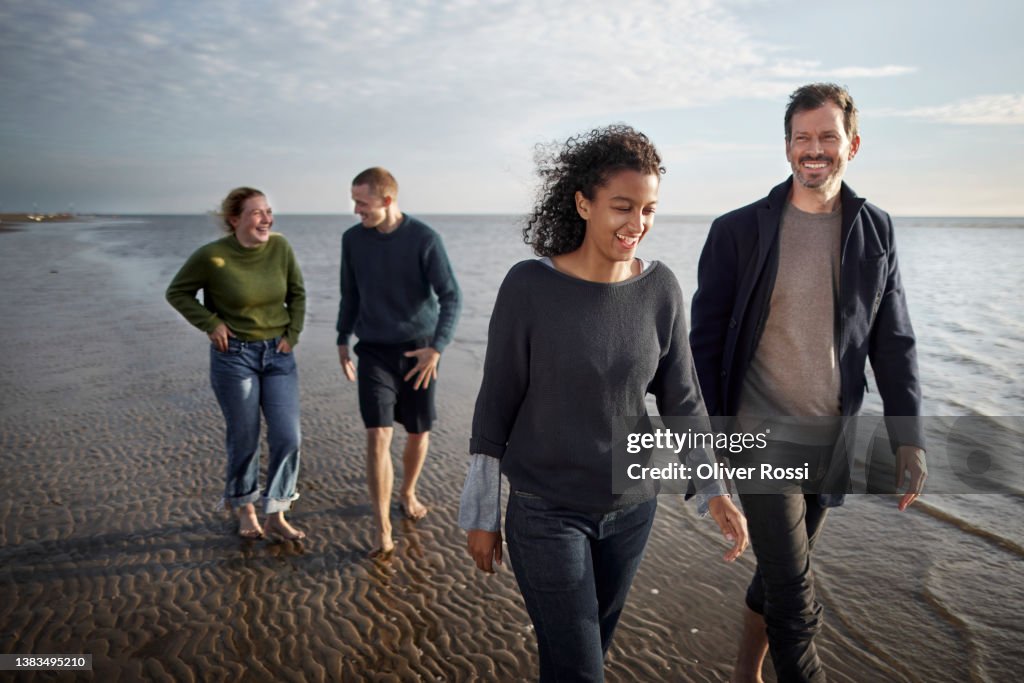 Group of friends walking by the sea at sunset
