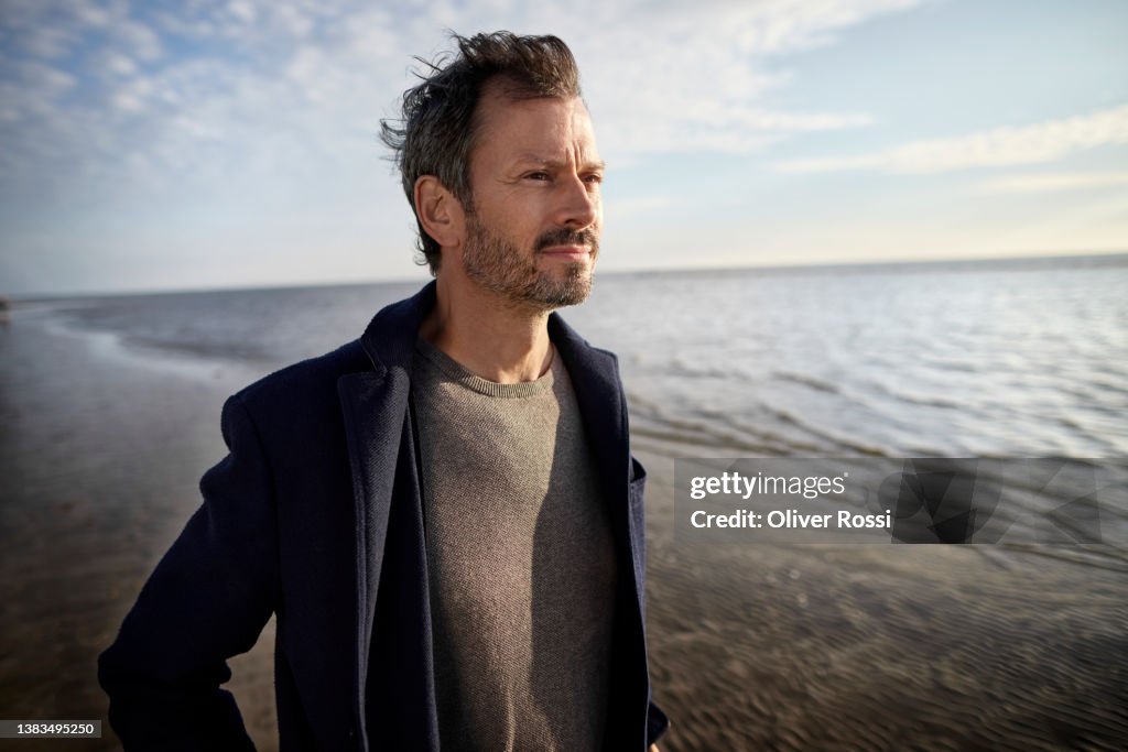 Mature man on the beach looking at view