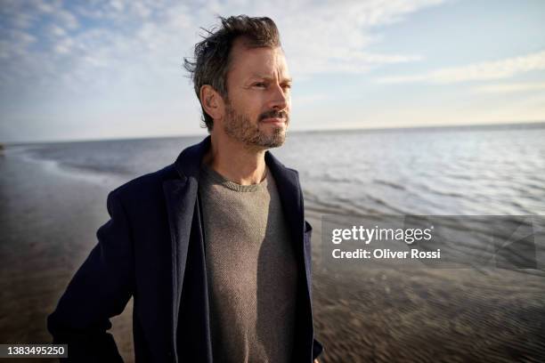 mature man on the beach looking at view - contemplation outdoors fotografías e imágenes de stock