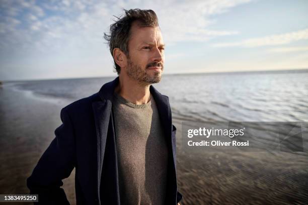 mature man on the beach looking at view - thinking man cloud stockfoto's en -beelden