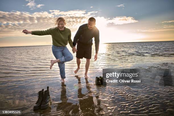 carefree young couple by the sea at sunset - vitality couple stock pictures, royalty-free photos & images