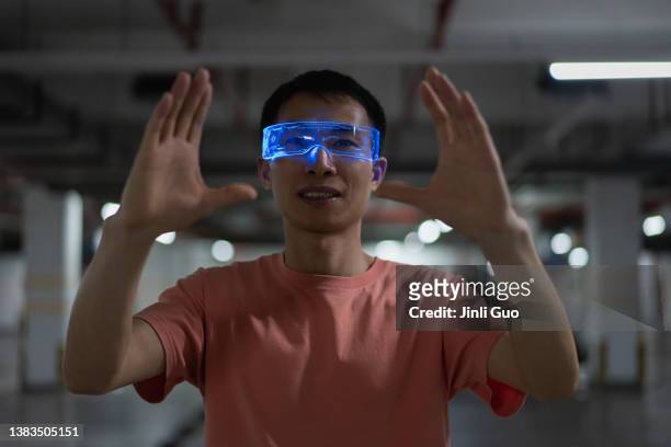 man uses vr glasses to experience virtual reality game in underground parking lot - night vision stock pictures, royalty-free photos & images