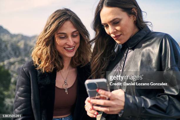 content ethnic female best friends using smartphone in mountainous valley - share content stock pictures, royalty-free photos & images