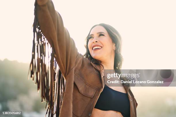 content woman in fringe jacket in nature - quaste stock-fotos und bilder