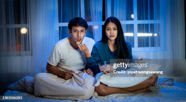 couples are excited from watching movies in the room at night, the concept of relaxation. social distancing - scary movie fotografías e imágenes de stock