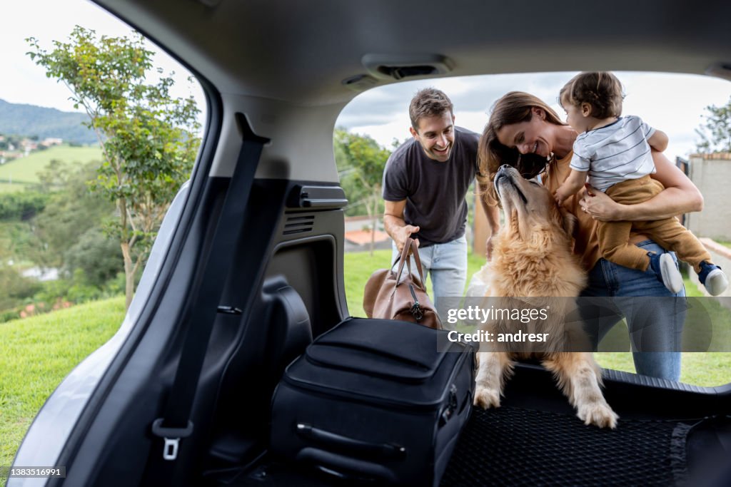 Happy family loading bags in the car and going on a road trip