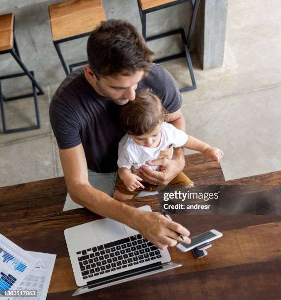 father trying to work at home and entertaining his son with online videos - work video call stock pictures, royalty-free photos & images