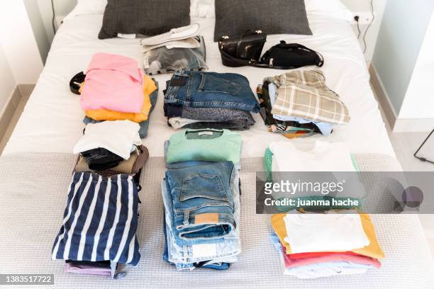 women's clothes folded over the bed, ready to store in the suitcase. - travel arrangement stock pictures, royalty-free photos & images