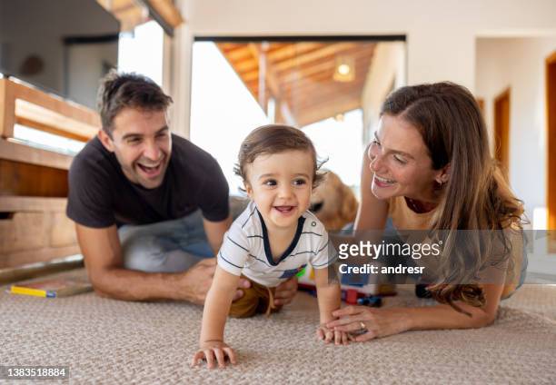 pais felizes vendo seu filho rastejando em casa - de quatro - fotografias e filmes do acervo