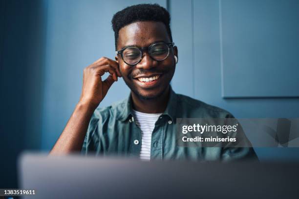 cheerful male student talking on a video call meeting on his laptop computer in a coffee shop - man on video call stock pictures, royalty-free photos & images