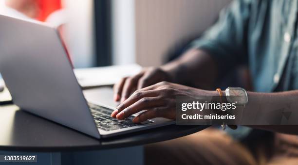 un estudiante anónimo usando su computadora portátil en un café - conformidad fotografías e imágenes de stock