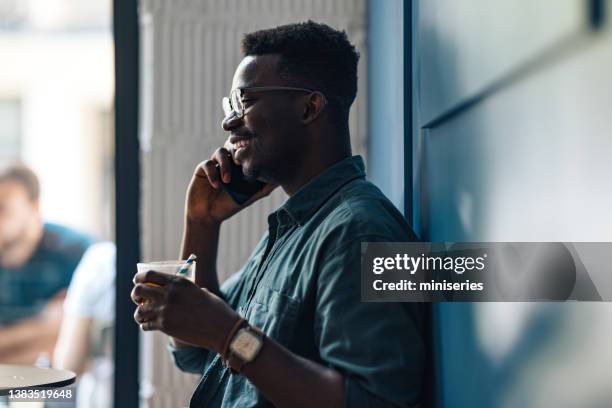 happy student talking on a mobile phone in a cafe - wanderer pause stockfoto's en -beelden